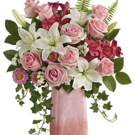 Pink roses and white lilies arranged in a pink vase