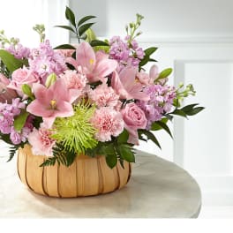 Pink floral arrangement in a woven basket on a table