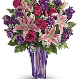 Pink lilies and roses in a purple glass vase