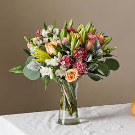 Mixed bouquet of lilies, roses, carnations, and alstroemeria in a glass vase
