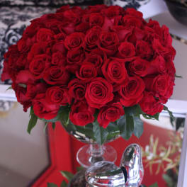 Large dome of red roses arranged in a clear pedestal glass vase