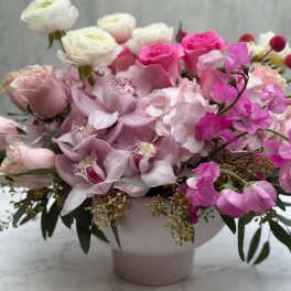Low pink and white arrangement with roses, orchids, ranunculus and hydrangeas in a blush ceramic bowl