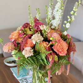 Mixed bouquet of peach and pink flowers in a clear glass vase