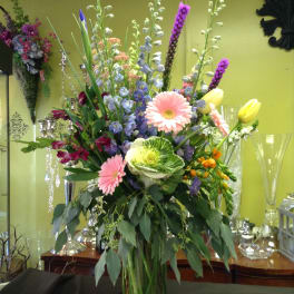 Tall mixed bouquet in a clear glass vase with pink, purple, and yellow blooms