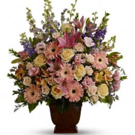 Large mixed flower arrangement in a dark vase with pink and cream blooms