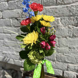Colorful mixed bouquet in a tall glass vase with a green ribbon