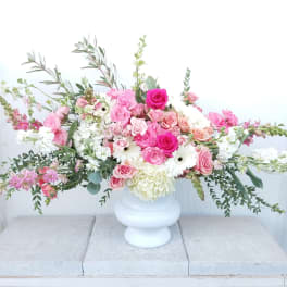Large pink and white floral arrangement in a white vase