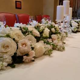 White floral centerpieces line a long table with tall candles