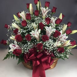 Basket arrangement of red roses and white lilies with a burgundy ribbon