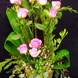 Pink roses arranged in a gold pot with greenery