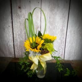 Sunflower arrangement in a glass vase with a yellow ribbon
