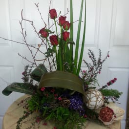 Tall arrangement of red roses with decorative branches and greenery