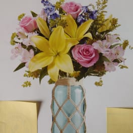 Bouquet of pink roses, yellow lilies, and purple flowers in a blue vase