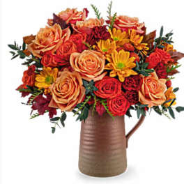 Bouquet of orange and red flowers in a brown pitcher vase