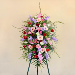 Tall standing floral spray with pink, red, and lavender flowers on an easel
