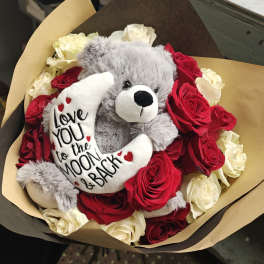 Bouquet of red and white roses with a gray teddy bear holding a moon pillow