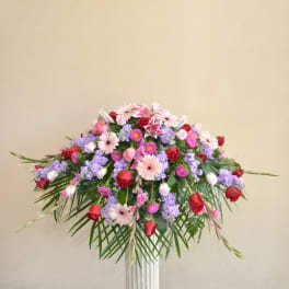 Large mixed bouquet with pink, red, and lavender flowers in a tall vase