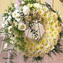 Standing wreath of white and cream roses and chrysanthemums on a metal easel