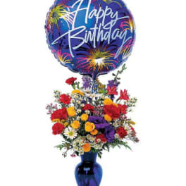 Colorful mixed flower arrangement in a blue vase with a large Happy Birthday balloon on top