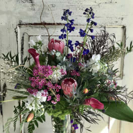 Mixed bouquet in a clear glass vase with pink, white, and blue flowers