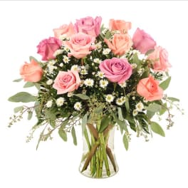 Pink and peach roses in a clear glass vase with small white filler flowers