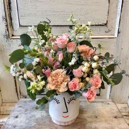 Pink and peach bouquet in a white face vase