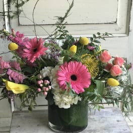 Mixed bouquet in a glass vase with pink gerberas, yellow tulips, and roses