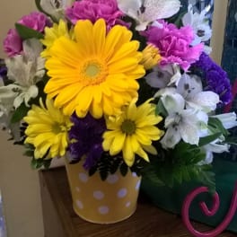 Bouquet of yellow daisies, purple carnations, and white alstroemeria in a polka-dot vase
