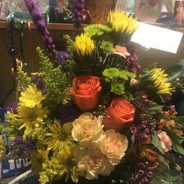 Colorful bouquet with orange roses, yellow daisies, and purple spikes