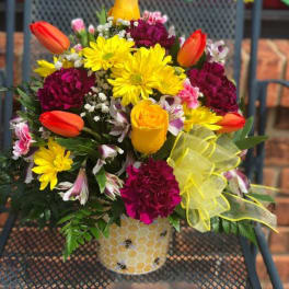 Bright mixed bouquet in a honeycomb-patterned vase with yellow ribbon