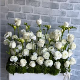 White roses and ranunculus arranged in a white box