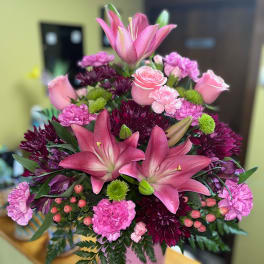 Pink lilies and roses arranged in a pink vase