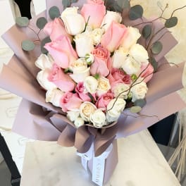 Bouquet of pink and white roses wrapped in mauve paper