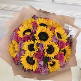Bouquet of yellow sunflowers and pink-purple roses wrapped in blush paper