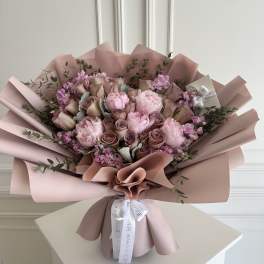 Pink and mauve bouquet of roses and peonies wrapped in blush paper