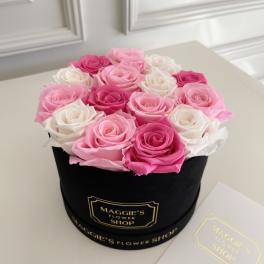 Pink and white roses arranged in a black round box