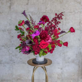 Bright pink and purple floral arrangement in a white vase