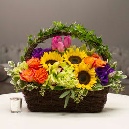 Basket arrangement with sunflowers, roses, orchids, and tulips