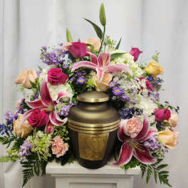 Floral arrangement surrounding a bronze urn with pink lilies and roses