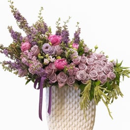 Lavender and pink floral arrangement in a textured cream vase