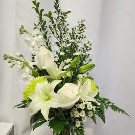 White lilies and roses in a glass vase with small white daisies