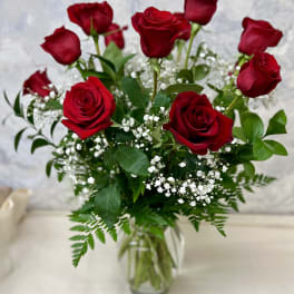 Arrangement of red roses with white filler flowers in a clear glass vase
