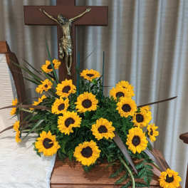 Sunflower arrangement displayed beside a wooden cross on a casket