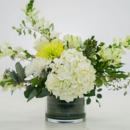 White and pale yellow floral arrangement in a glass vase
