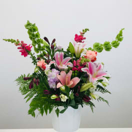 Mixed pink and white floral arrangement in a white pedestal vase