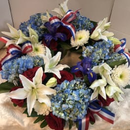 Wreath of blue hydrangeas, white lilies, red roses, and ribbon bows