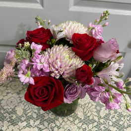 Bouquet of red and lavender roses with pink and white blooms in a glass vase