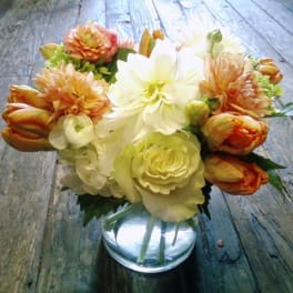 Bouquet of cream and orange flowers in a clear glass vase