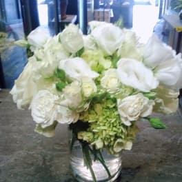 White roses and hydrangeas arranged in a clear glass vase