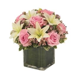 Pink roses and white lilies arranged in a square glass vase